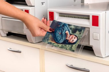 Elini ve makine görünümü kadar yakın bir yazıcıda bir gülümseyen güzel kadın bir renkli fotoğraf baskı alarak kadın