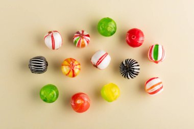 Birkaç yukarıdan izlendi düz bej renkli arka plan üzerinde renkli şekerler, lolipop topları, yuvarlak