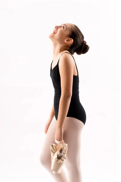 快乐的年轻芭蕾舞演员拿着她的粉红色芭蕾鞋抬头笑着 她的头向后倾斜 在白色的近顶侧视图 — 图库照片