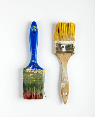 İki eski kirli ahşap boya fırçaları sarı ve kahverengi boya lekeleri beyaz bir DIY, tadilat, iç dekorasyon veya bakım kavramı üzerine