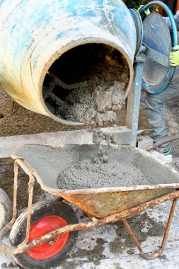 İşçi el arabasına çimento yüklüyor