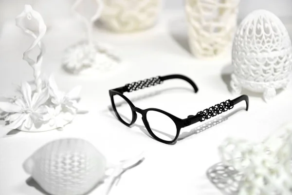 Beyaz örnekler arasında 3d baskılı siyah gözlük — Stok fotoğraf