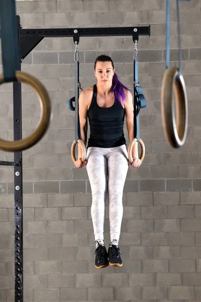Young woman doing muscle up exercises on rings