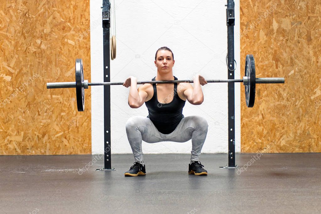 Muscular young woman doing a front squat