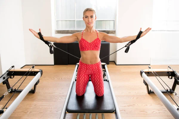 Mulher fazendo pilates braço trabalho com tiras — Fotografia de Stock