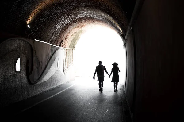 Couple walking hand in hand through a tunnel — Stock Photo, Image