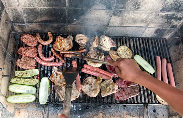 Persona che cucina carne e verdure assortite sul barbecue — Foto Stock