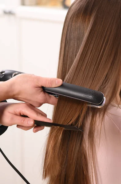 Pessoa não identificável usando alisador de cabelo — Fotografia de Stock