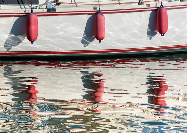 Três pára-lamas vermelhos pendurados sobre o casco de um barco — Fotografia de Stock