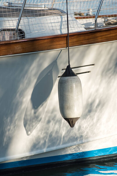 White fender hanging on the hull of a sailboat