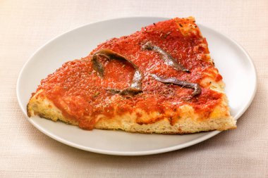 Domates ezmesi üzerine ançüezli tek dilim Marinara pizzası. Yakın plan beyaz tabakta servis edilir.