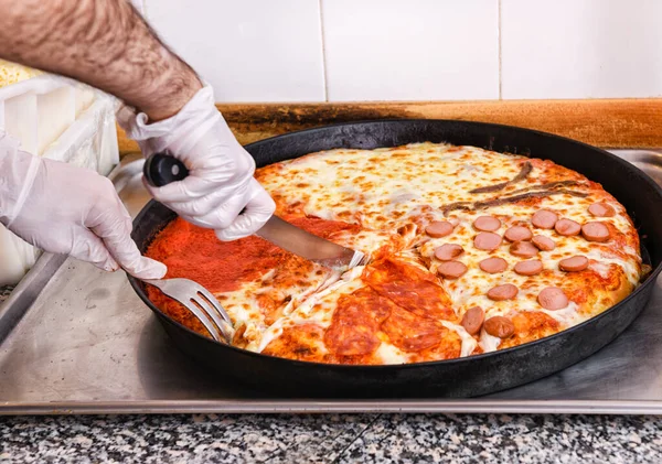 シェフは ナイフを使用して4種類のトッピングでイタリアのピザをスライスし 彼の手の上にクローズアップでピッツェリアキッチンでフォーク — ストック写真