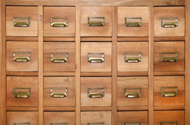 Simetrik tam çerçeve arkaplan görünümünde pirinç saplı ve etiket tutucuları olan küçük tahta çekmeceli dolap