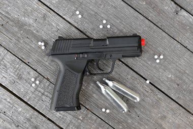 Karbondioksit kutuları ve metalik olmayan çekimler içeren hava yumuşağı ya da Softair tabancası düz bir ahşap arka planda düz bir yaşam sürüyordu.