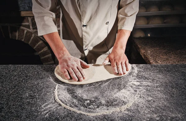 Una masa para una pizza en manos del chef . — Foto de Stock