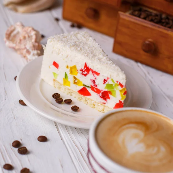 Bir tabloda bir fincan kapuçino ve kabukları ile renkli jöle ile pasta.