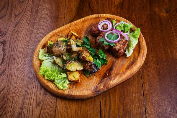 Tabla con barbacoa y papas al horno en una mesa de madera —  Fotos de Stock