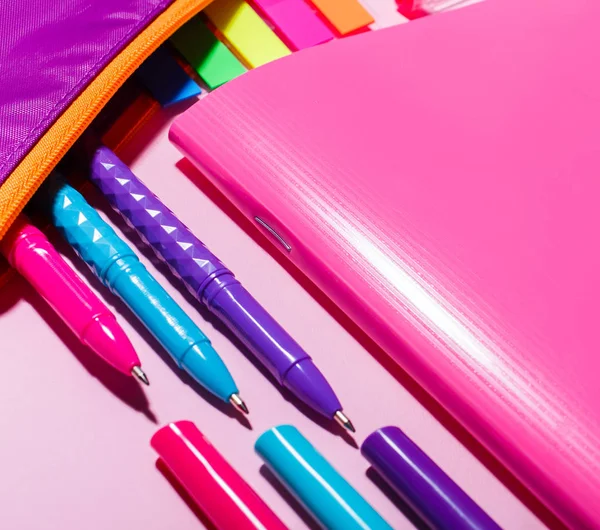 Un cuaderno rosa junto a bolígrafos brillantes — Foto de Stock