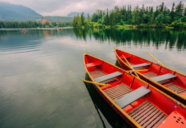 Dağ gölü içinde Yüksek Tatras Ulusal Park. Strbske Pleso, Slovakya. Bir bulutlu gökyüzü altında bir göl kenarında iki kırmızı tekne.