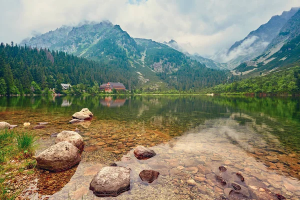 Jezioro jest wysoki w górach w chmurach. Hotel w pobliżu jeziora w górach. — Zdjęcie stockowe