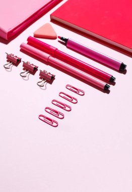 Pembe ataç, pembe defter ve pembe kalem dava pembe bir arka plan üzerinde.