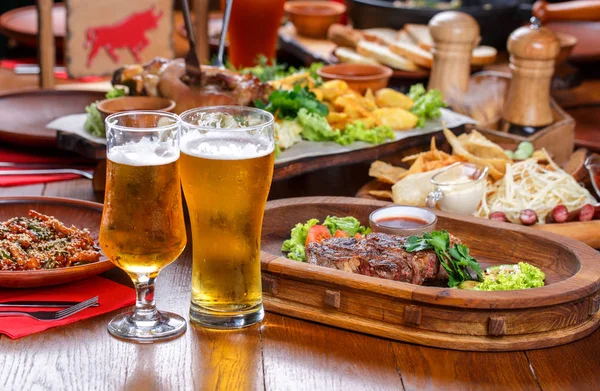 Mesa de cerveza en el pub. Filete caliente con salsa y verduras . — Foto de Stock