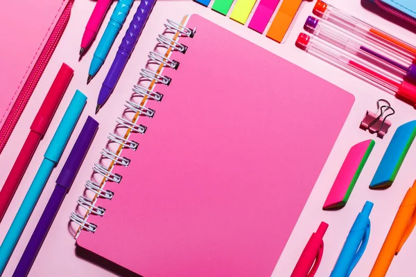 Un cuaderno rosa junto a bolígrafos brillantes — Foto de Stock