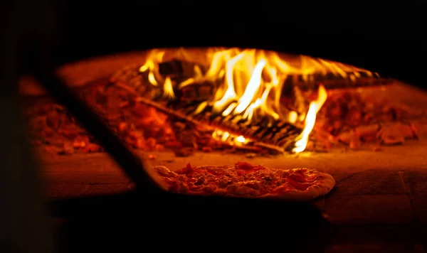 Pizza in the oven. A good fire burns in the oven.