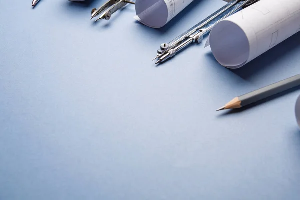 Tools for drawing and rolls of blueprints on a blue background — Stock Photo, Image