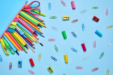 Parlak büro malzemeleri açık mavi arka planı üzerinde dağılmış