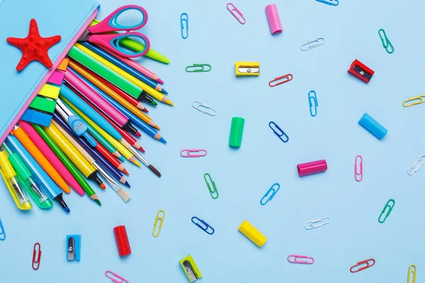 Colored pens, pencils, markers and other objects lie on a light
