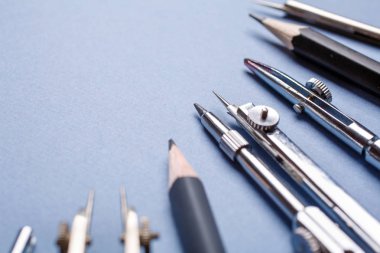 Açık mavi arka plan üzerinde pusulalar ve kalemler