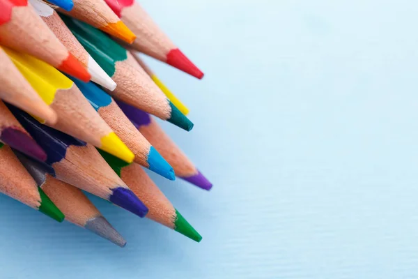 En grupp av ljusa trä blyertspennor liggande på en blå bakgrund — Stockfoto