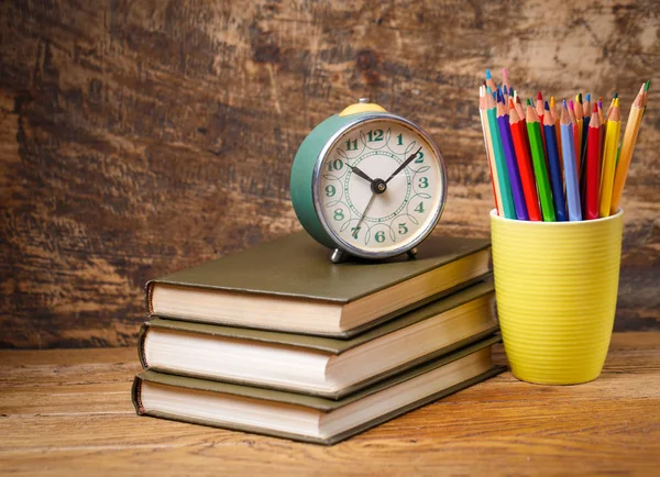 Un viejo reloj en los libros sobre la mesa en el estudiante — Foto de Stock