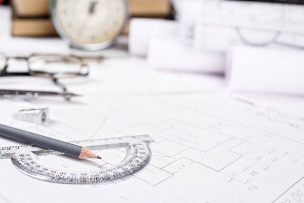 A pencil with a protractor on the background of books, watches a