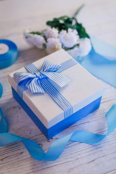 Confezione regalo con fiocco. Nastri di raso blu e appliques foglia. Fiori — Foto Stock