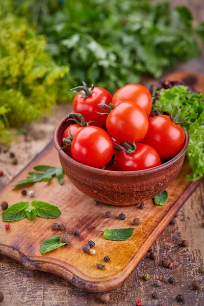 Plate with tomatoes on the background of herbs — Stock Photo, Image