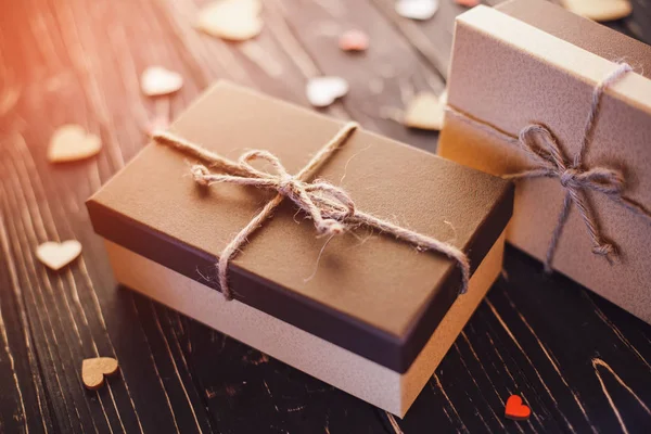 Two brown gift boxes on a wooden background with a bow of a simple rope on wood backgraund.