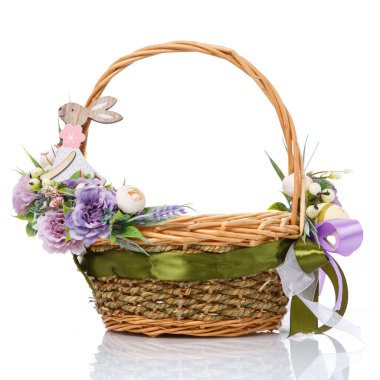 Beyaz arka planda Paskalya sepeti. Mor çiçekler ve küçük dekoratif ahşap bir tavşanla süslenmiş. Yan görünüm.