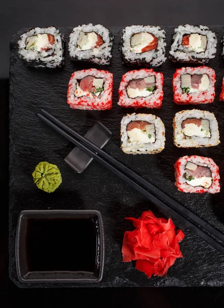 Původně dát sadu sushi na černou tabuli. S hůlkami, zázvorem, wasabi a sójovou omáčkou. — Stock fotografie
