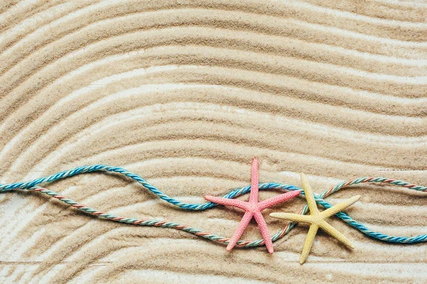 波状の砂の上に2色のヒトデと2色の海洋ロープ 最上階だ コピースペース付き夏の背景の概念 — ストック写真