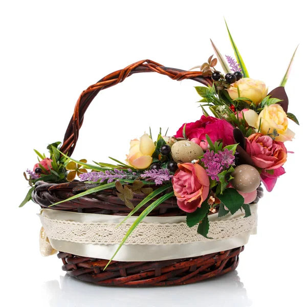 Cesta de mimbre marrón oscuro con mango original y decoración floral sobre fondo blanco. Decoración de flores amarillas y rosadas, verde. cinta ancha y encaje . — Foto de Stock