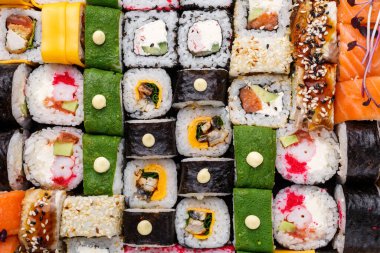 Suşi arka planda. Farklı dolgulu dev rulo. Somon, ton balığı, yılan balığı, avokado, salatalık, Philadelphia, pirzola ve havyar..