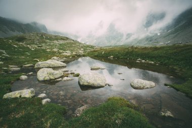 High Tatras 'taki sisli dağlarda bir göl. Slovakya. Sisteki dağların arka planına karşı kristal berrak bir göl manzarası.