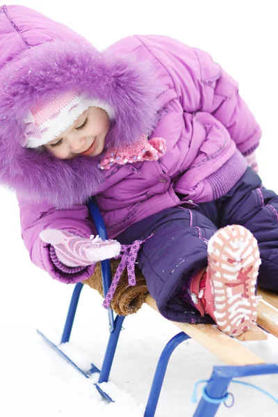 Flicka på slädar ser på snön i hennes hand — Stockfoto