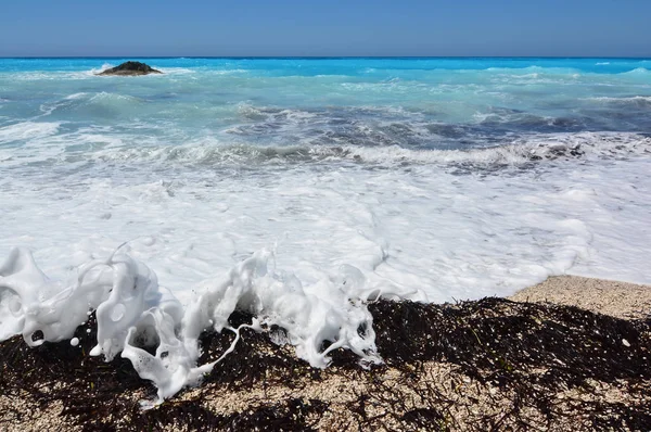 Onde bianche su alghe e alghe nere — Foto Stock