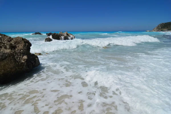 Rocas Oscuras Salpicadas Olas Agua Turquesa Espuma Blanca Cielo Azul —  Fotos de Stock