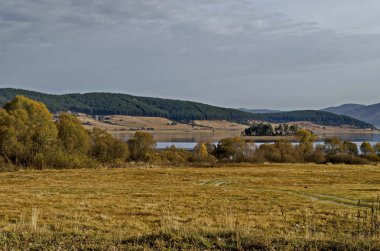 Glade, hill, kıyı, yapraklı ve iğne yapraklı ağaçlar etrafında Batak Baraj Gölü, Rodop Dağları, Bulgaristan ile orman şaşırtıcı sonbahar manzarası 