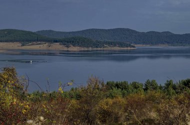 Glade, hill, kıyı, yapraklı ve iğne yapraklı ağaçlar etrafında Batak Baraj Gölü, Rodop Dağları, Bulgaristan ile orman şaşırtıcı sonbahar manzarası  
