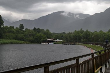 Bulgaristan'ın Dupnitsa kasabası yakınlarındaki Rila parkında yağmurlu bir günde barınak ve teknelerle dolu yapay bir göl manzarası  
